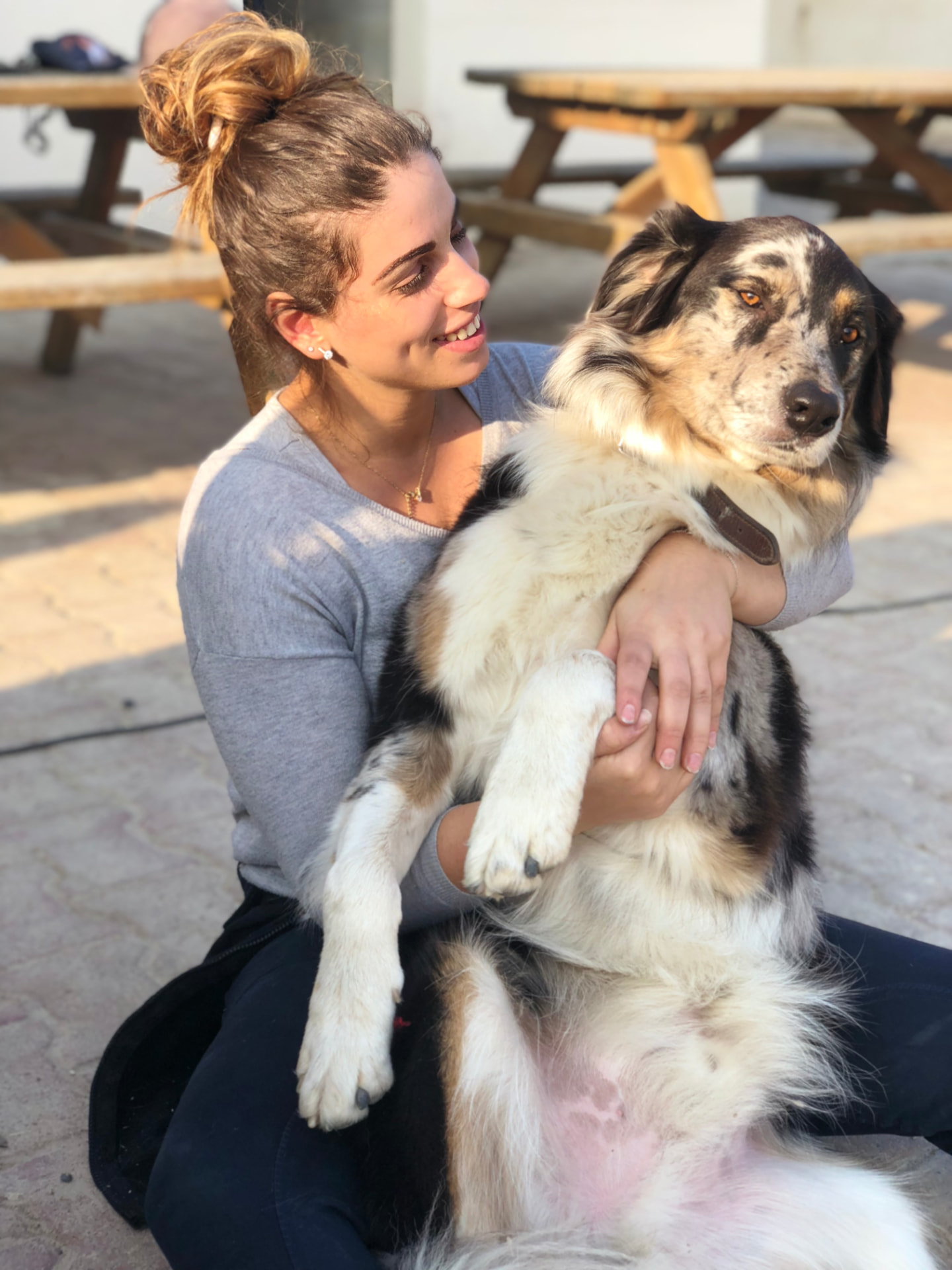 Lia tenant un jeune chien dans ses bras, en extérieur